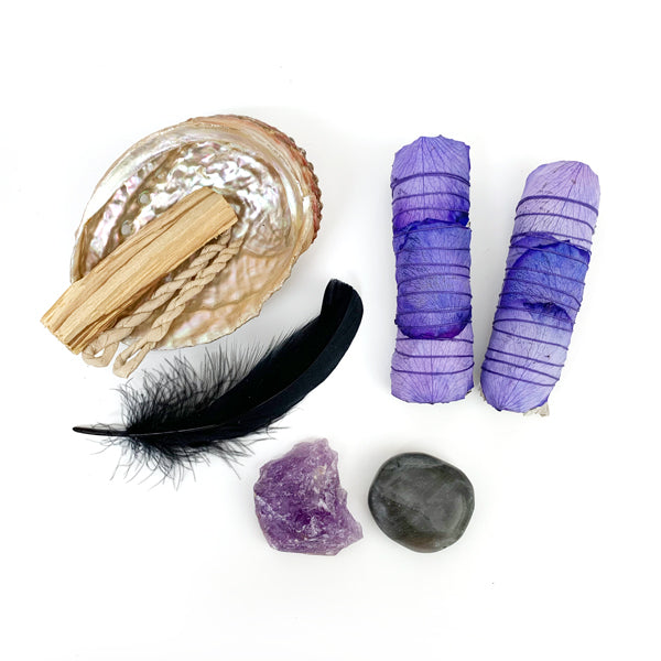 Two Purple Rose Wrapped White Sage Sticks, Abalone Shell, Palo Santo Sticks, Black Feather, Raw Amethyst Stone, And Black Moonstone.